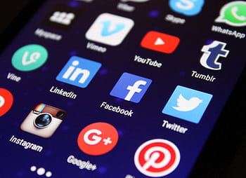 Close-up of a smart screen showing various social media app icons such as Facebook and Twitter. HD wallpaper