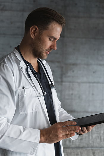 Portrait of a confident male doctor using a tablet indoors. HD phone wallpaper