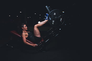 A woman engages in an intense leg press workout at the gym, showcasing strength and fitness. HD wallpaper