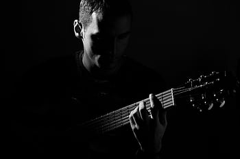 A captivating black and white portrait of a guitarist in an artistic pose, playing guitar. HD wallpaper