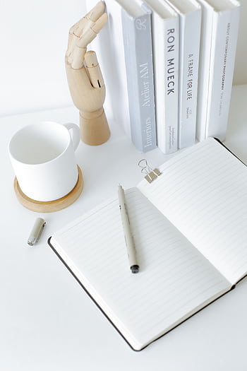 A clean and organized desk setup featuring an open notebook, books, and a mug, perfect for a modern workspace. HD phone wallpaper