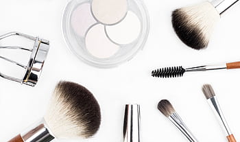 Flat lay of various makeup brushes and tools on a white background. HD wallpaper