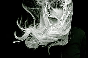 A striking black and white portrait of a woman with long, flowing hair that creates a sense of motion and mystery. HD wallpaper