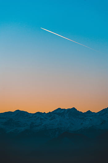 Scenic mountain view at sunset with a contrail streaking across the sky. HD phone wallpaper