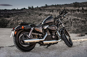 A parked Harley Davidson motorcycle on a gravel path with a scenic background, exuding dom and adventure. HD wallpaper