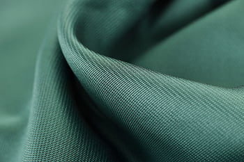 Close-up texture shot of elegant green satin fabric highlighting its smooth and soft surface. HD wallpaper