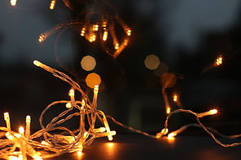 Close-up of glowing string lights creating a cozy ambiance with warm bokeh background. HD wallpaper