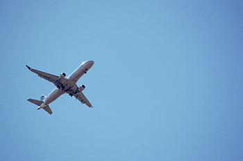 A commercial airplane captured mid-flight against a clear blue sky. HD wallpaper