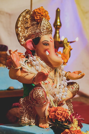 Beautifully adorned Ganesha statue with vibrant flowers, representing traditional Hindu culture. HD phone wallpaper
