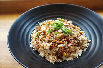 Delicious homemade fried rice with scallions and sauce on a black plate. HD wallpaper