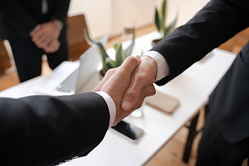 Close-up of a handshake between two professionals in a business setting, symbolizing agreement. HD wallpaper