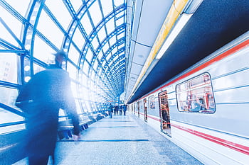 Blurred commuters rushing in a modern subway station with striking architecture and light play. HD wallpaper