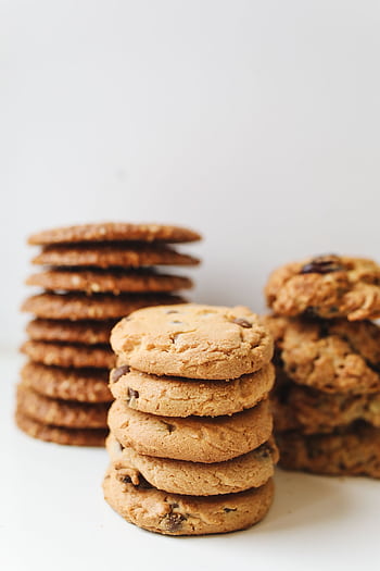A variety of delicious homemade cookies stacked neatly in piles on a white background. HD phone wallpaper