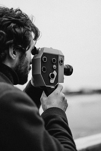 Profile of a man filming with a vintage camera outdoors. Black and white. HD phone wallpaper
