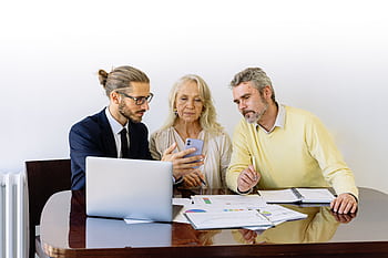 Three individuals collaborating on financial documents during a business meeting. HD wallpaper