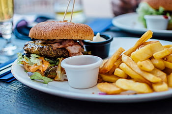 Close-up of a juicy burger and crispy fries served with sauces, perfect for a hearty meal. HD wallpaper