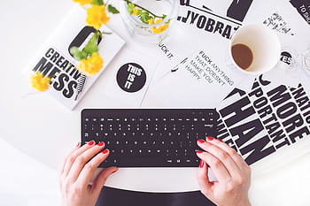 A creative workspace featuring a woman typing with red nails, surrounded by inspirational typography. HD wallpaper