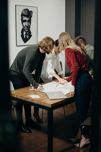 Group of diverse professionals brainstorming ideas in a stylish modern office space. HD phone wallpaper
