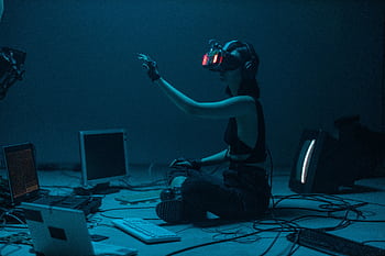 Woman immersed in virtual reality, surrounded by tech, in a dimly lit room. HD wallpaper