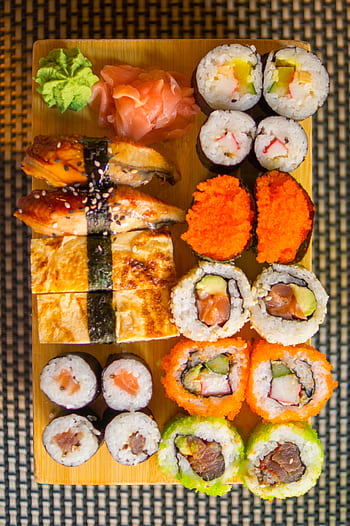 Delicious sushi platter featuring diverse nigiri and maki rolls with fresh ingredients. HD phone wallpaper