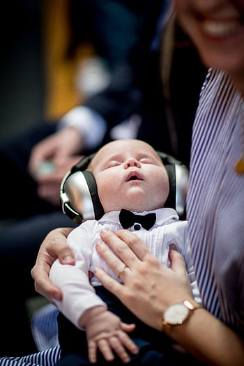 A cute baby wearing heads and a bow tie sleeping peacefully in an indoor setting. HD phone wallpaper