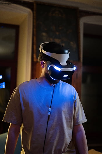 A young man using a VR headset in a dimly lit room indoors, showcasing virtual reality technology. HD phone wallpaper