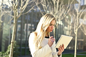 A young woman using her tablet and smart outdoors in a city park. HD wallpaper