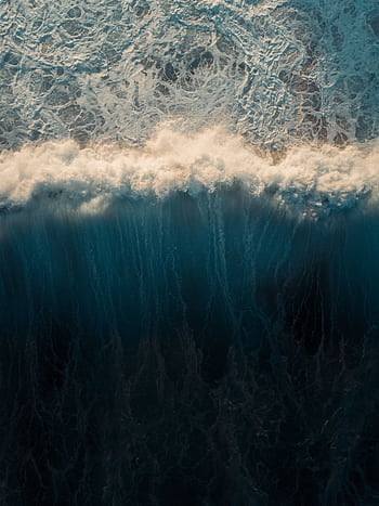 Stunning aerial capture of ocean waves crashing and creating a mesmerizing water pattern. HD phone wallpaper