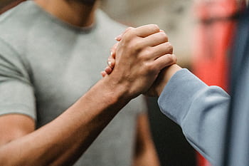 Close-up of a handshake between two individuals in a gym, symbolizing support and teamwork. HD wallpaper