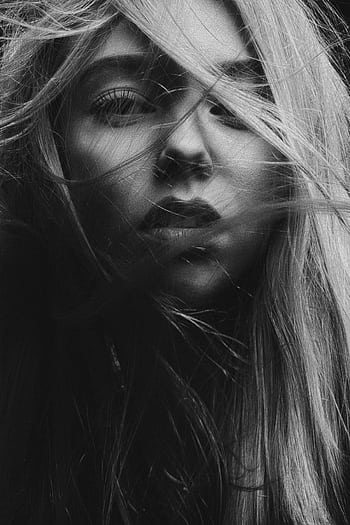 A dramatic black and white portrait capturing a woman's face with flowing hair. High contrast mood. HD phone wallpaper