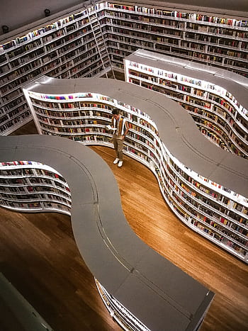 A modern library interior featuring unique curved bookshelves viewed from above, with a man reading. HD phone wallpaper