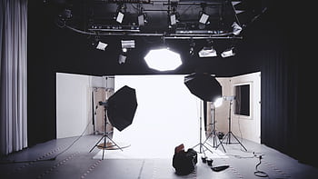 A well-equipped graphy studio featuring lights, softboxes, and a white backdrop for professional shoots. HD wallpaper