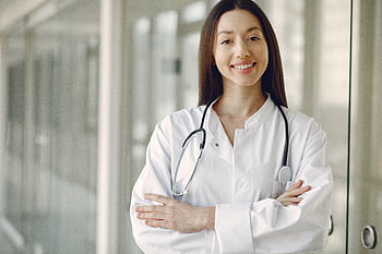 Portrait of a smiling female doctor with arms crossed and stethoscope in a hospital corridor. HD wallpaper