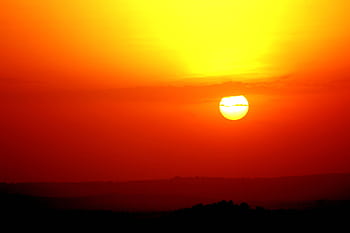Stunning view of a vibrant sunset with orange and red skies over a serene landscape. HD wallpaper