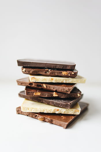 Assorted stacked chocolate bars featuring white, milk, and dark varieties with nut inclusions. HD phone wallpaper