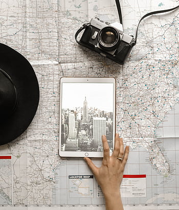 Flat lay of vintage camera, iPad with New York City skyline, and a hand on a map. HD phone wallpaper