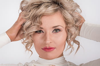 Close-up portrait of a blonde woman with curly hair and makeup, embracing elegance. HD wallpaper