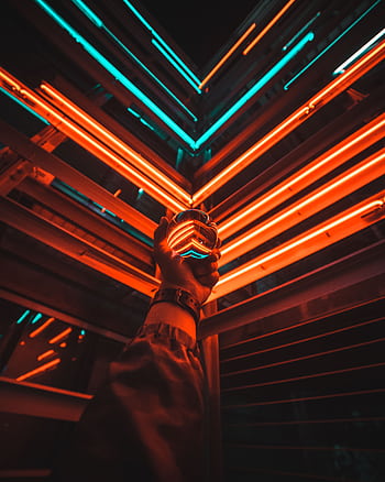 A hand holding a glowing glass ball reflecting vibrant neon lights in an urban setting at night. HD phone wallpaper
