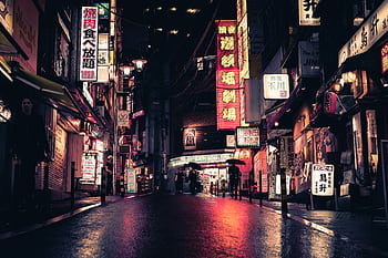Neon-lit street in Tokyo showcasing urban nightlife, bustling with people and striking signage. HD wallpaper