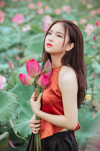 Asian woman elegantly posing with lotus flowers in an enchanting garden setting. HD phone wallpaper