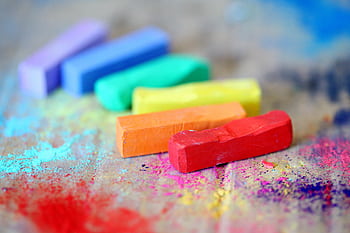 Vibrant pastel chalks on colorful splattered canvas, perfect for creative arts and crafts inspiration. HD wallpaper