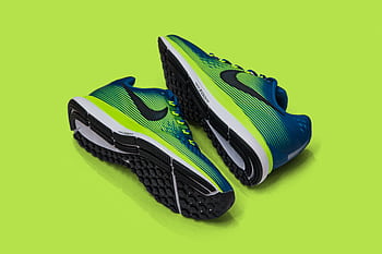 Modern blue and green sports sneakers on a vibrant green background, perfect for athletic fashion. HD wallpaper
