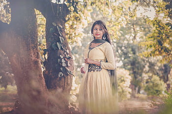 Portrait of a woman in traditional South Asian attire standing outdoors under trees. HD wallpaper