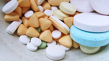 Close-up of various colorful pills and tablets on a neutral surface. HD wallpaper