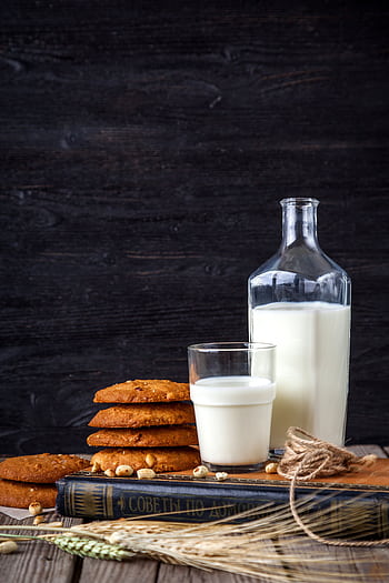 Glass of milk with stack of cookies, book, and bottle on a rustic wooden table. HD phone wallpaper