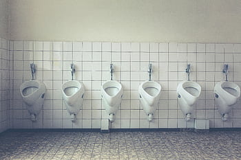 A modern and tidy restroom with a row of white urinals and tiled walls and floors. HD wallpaper
