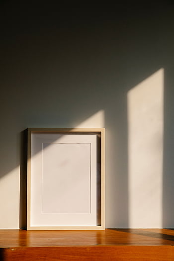 Elegant minimalist frame on a wooden shelf, bathed in warm sunlight. Perfect for interior decor concepts. HD phone wallpaper