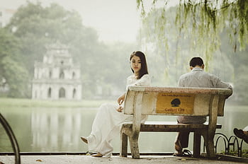 A couple sitting on a bench near Hanoi's iconic Turtle Tower, seemingly deep in thought. HD wallpaper