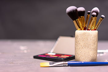 A stylish display of makeup brushes in a holder alongside a colorful palette. HD wallpaper