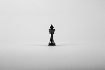 A minimalist black chess king piece on a white background, representing strategy and power. HD wallpaper